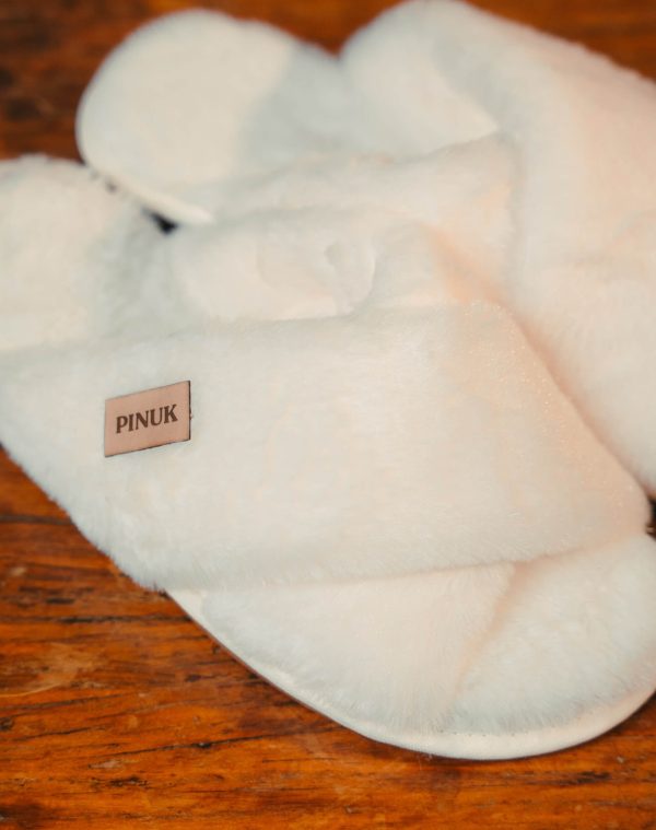 Pantufa Anatômica X Branca felpuda de tiras cruzadas com etiqueta Pinuk sobre piso de madeira