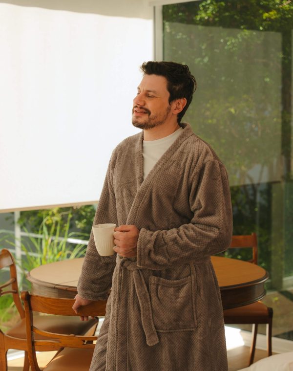 Roupão Polo Mineral vestido por homem de olhos fechados segurando caneca perto da mesa de jantar