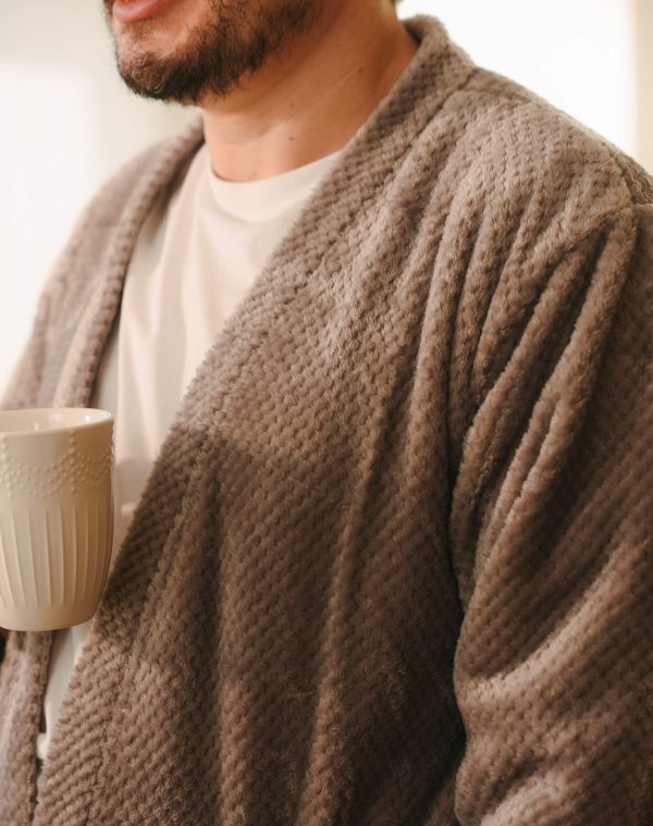 Roupão Polo Mineral felpudo em close, usado sobre camiseta branca por homem segurando caneca