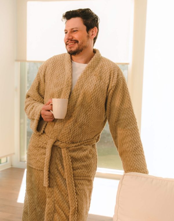 Roupão Polo Cerrado bege vestido por homem sorridente segurando caneca branca em sala iluminada