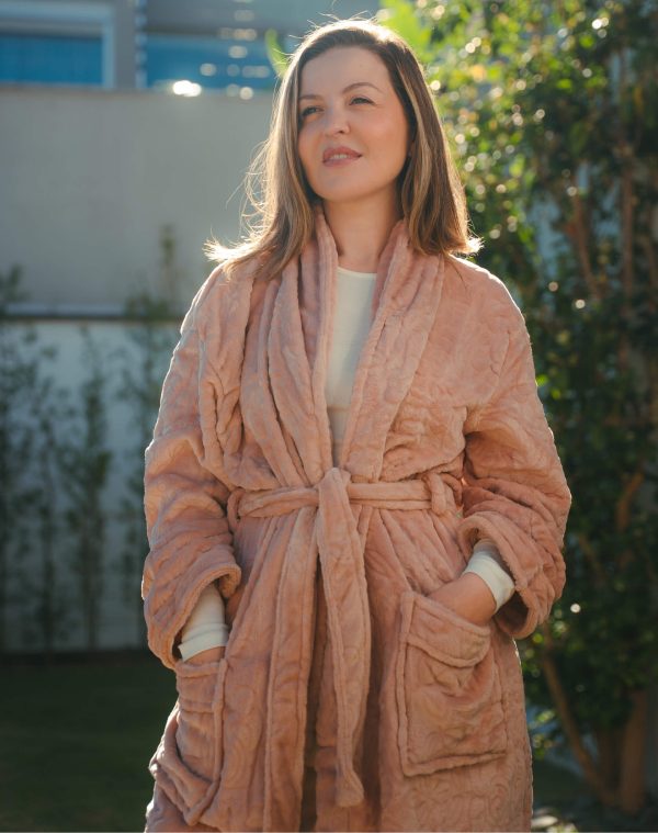 Roupão Lady Amarula rosa-antigo vestido por mulher em jardim ensolarado, com as mãos nos bolsos