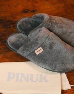 Pantufa Silver Cinza Estampada felpuda sobre saquinho de tecido Pinuk em piso de madeira